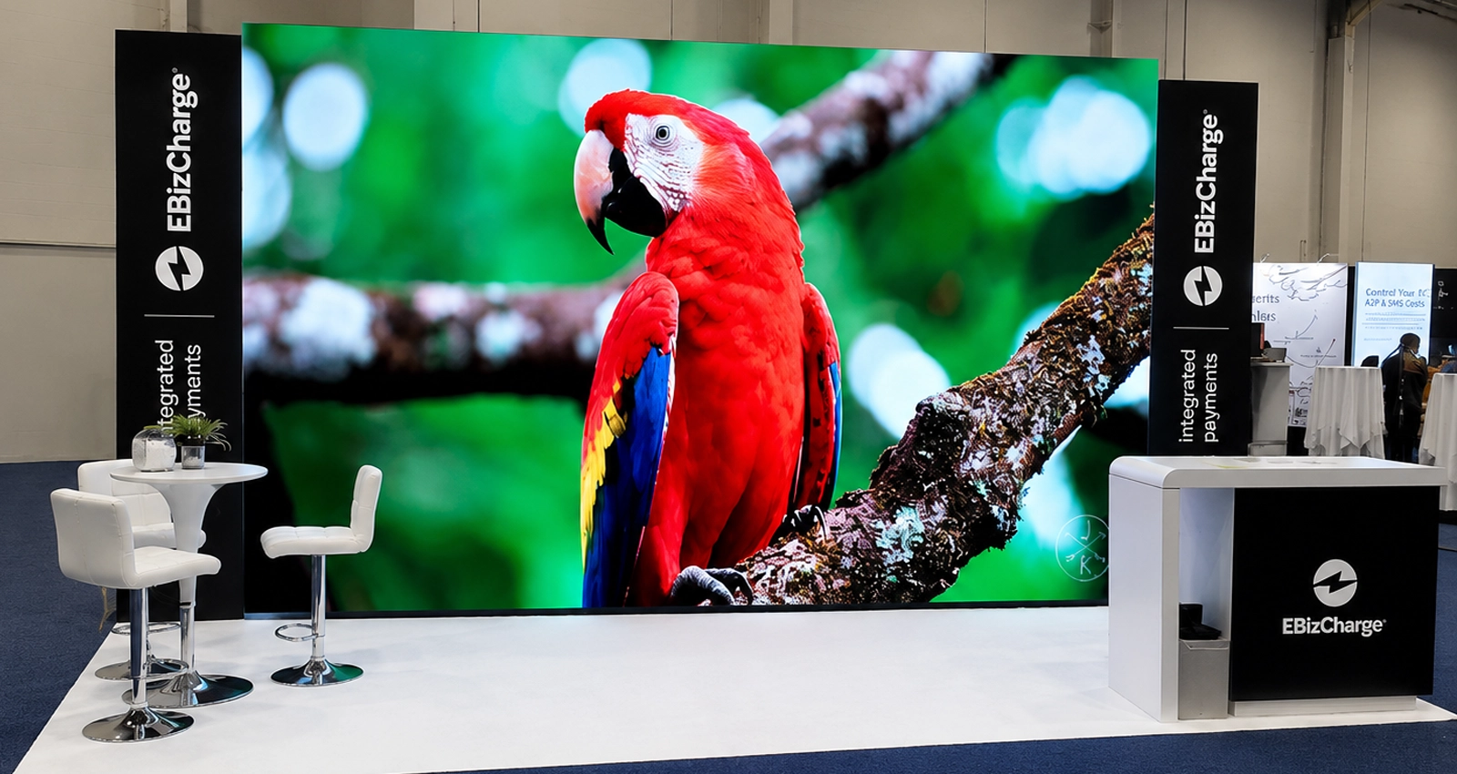 20x10 LED trade show exhibit with oversized video wall, lighting, branded towers, seating, reception counter and strong aisle visibility